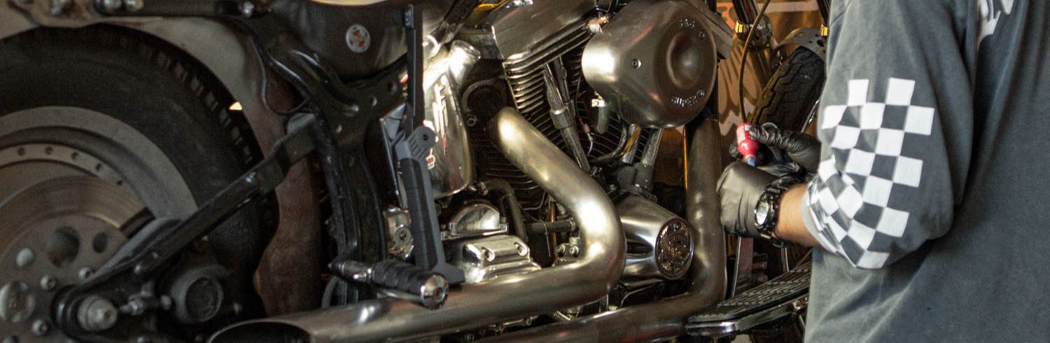 Mechanik pracujący przy motocyklu Harley-Davidson w serwisie Warszawa, specjalistyczny warsztat customizacji motocykli Harley-Davidson, mechanik dba o każdy detal